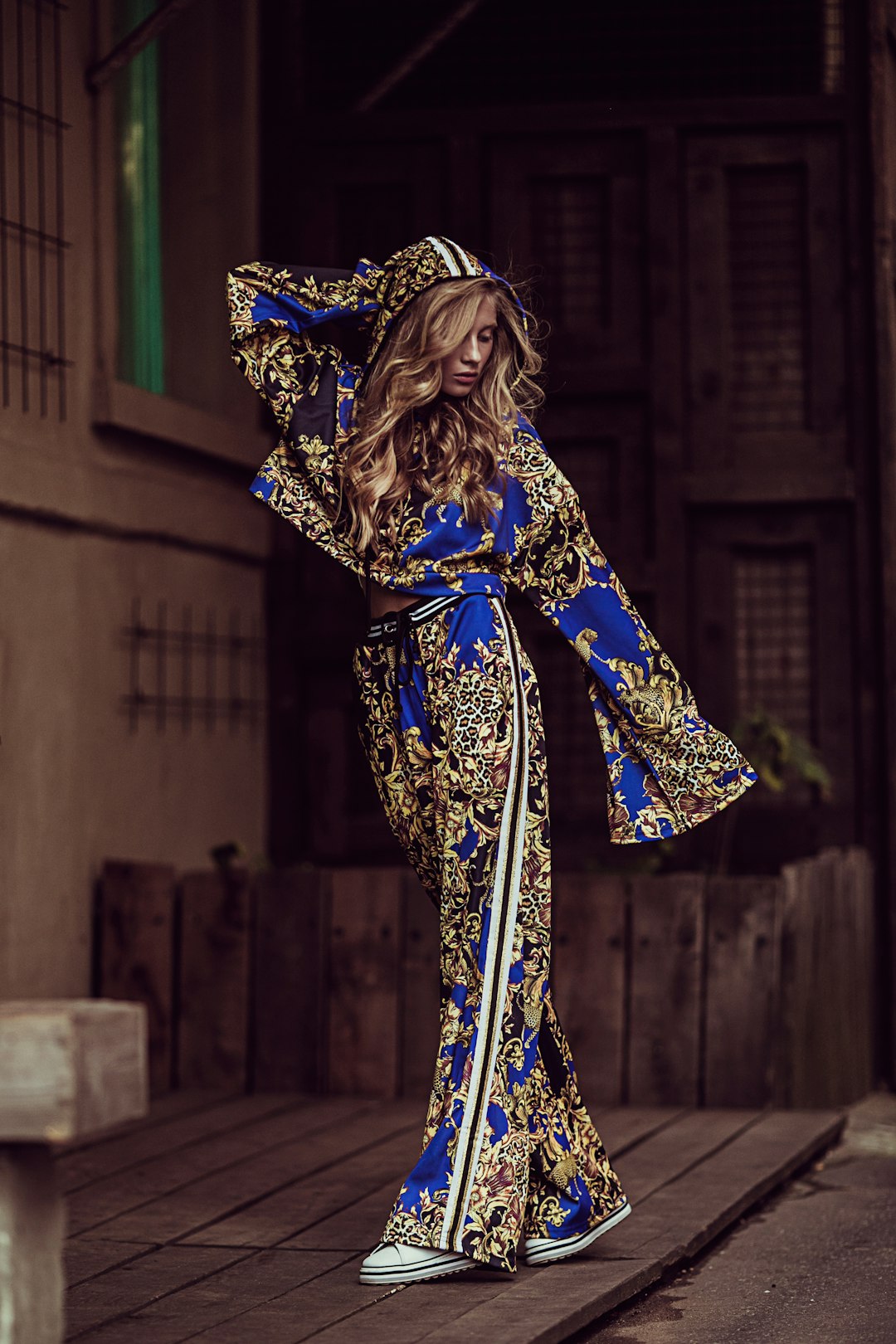 Stylish woman posing in baroque patterned tracksuit and sneakers.