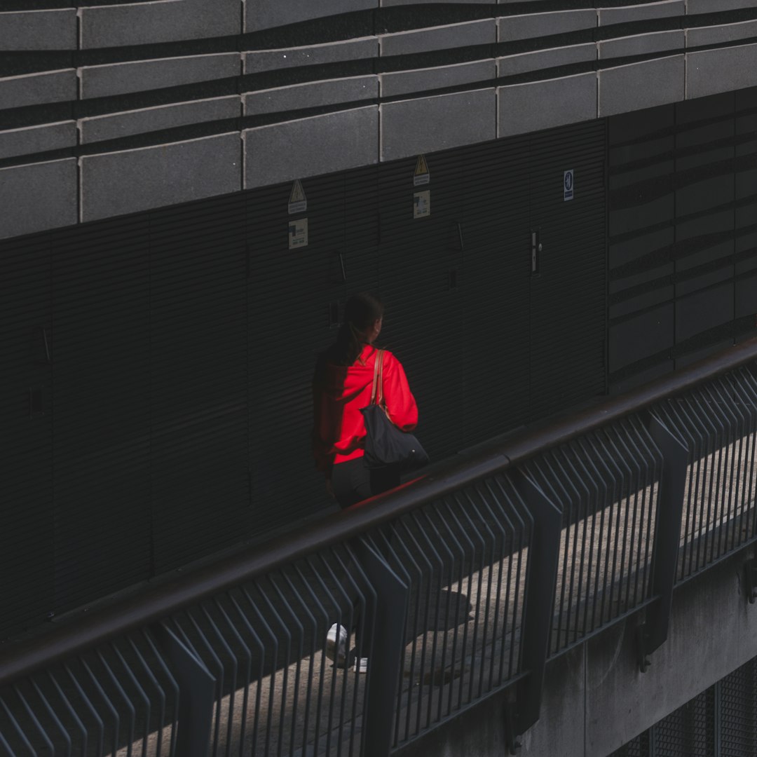 Person in red jacket walks on elevated walkway.