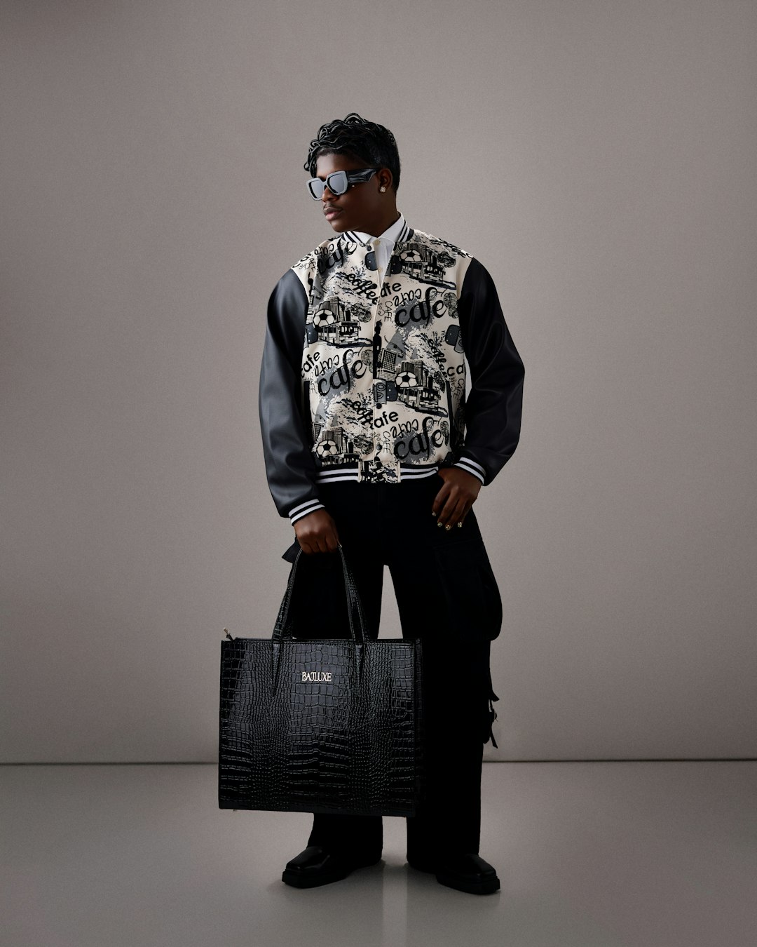 Stylish person in bomber jacket holding a black tote bag.